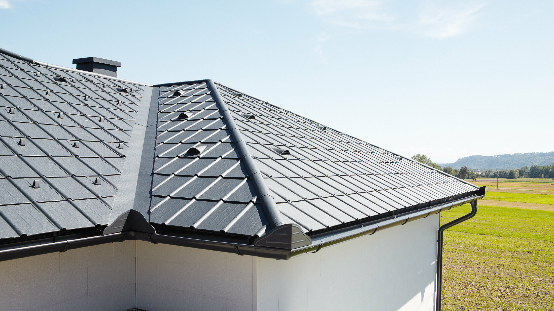 Detached bungalow, the roof is covered with PREFA roof tiles and the gutter in anthracite, you can also see a valley