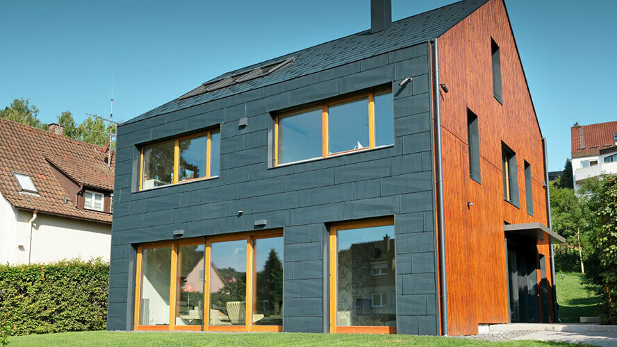 The PREFA FX.12 façade in P.10 anthracite extends from the façade over the gable roof without any overhang.