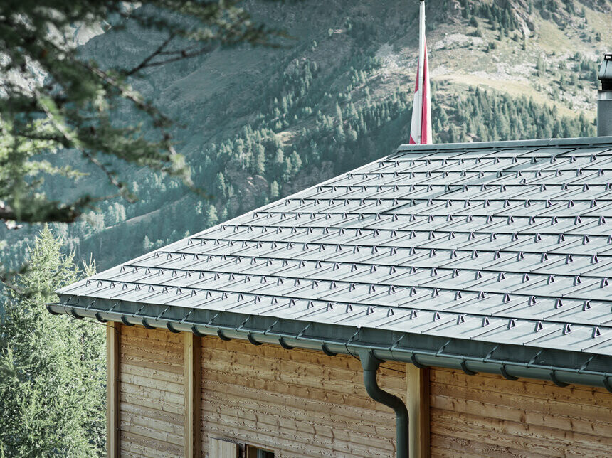 Swiss cabin covered with PREFA roof tiles and with the PREFA half-round gutter, which is attached with the overbar.