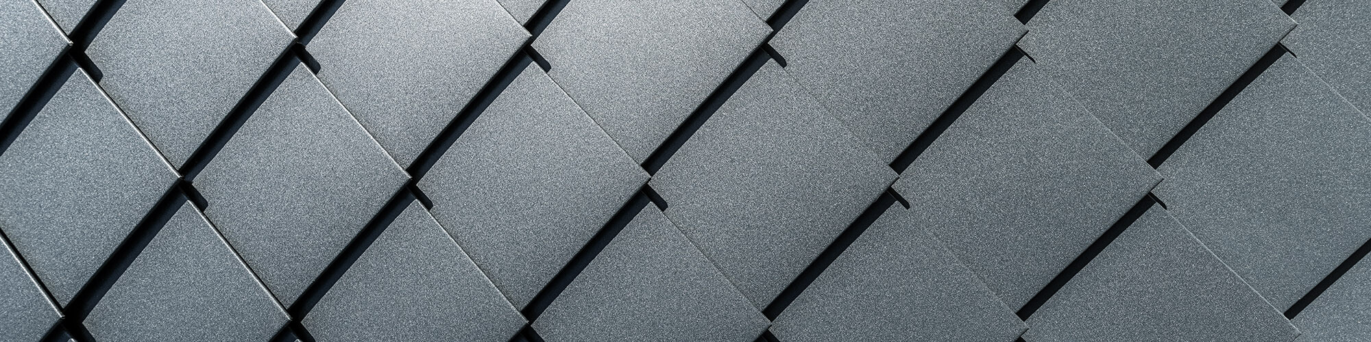 A close-up of the façade with the precisely laid, anthracite-coloured rhomboid facade tiles.