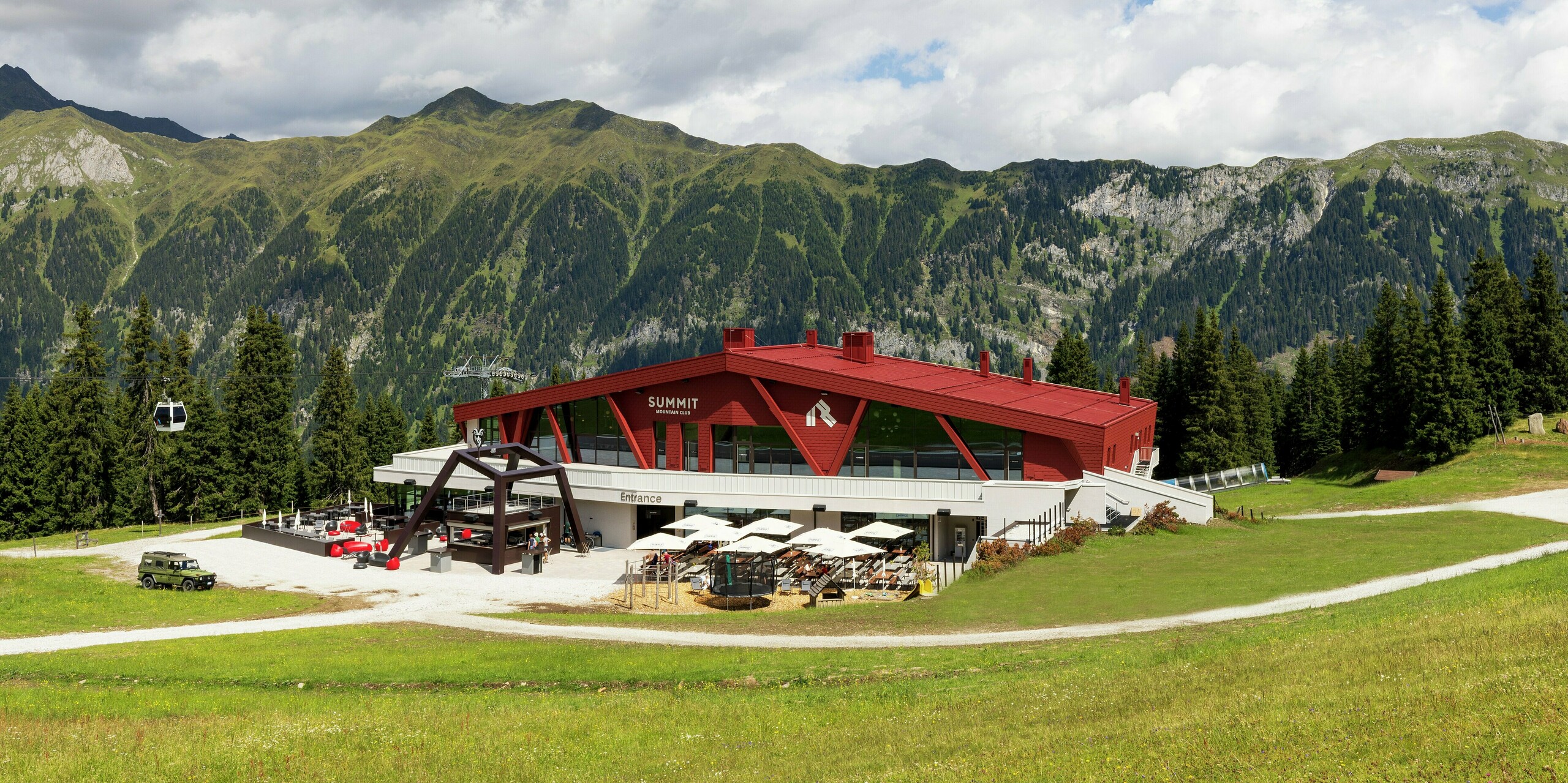 Der Summit Mountain Club in Ratschings beeindruckt mit seiner markanten Architektur, dem auffälligen Design und dem beeindruckenden Bergpanorama im Hintergrund. Das kräftig rote Dach und die Fassade setzen einen spannenden Kontrast zur alpinen Landschaft in den Sommermonaten. Das PREFALZ-Dachsystem aus robusten Stehfalzbahnen und die PREFA Wandschindeln auf der Fassade garantieren eine hohe Widerstandsfähigkeit gegenüber extremen Wetterbedingungen wie Schnee, Eis, Wind und Sonne. Das langlebige Material sorgt nicht nur für optische Highlights, sondern auch für langfristigen Schutz und Nachhaltigkeit in der rauen Bergregion.