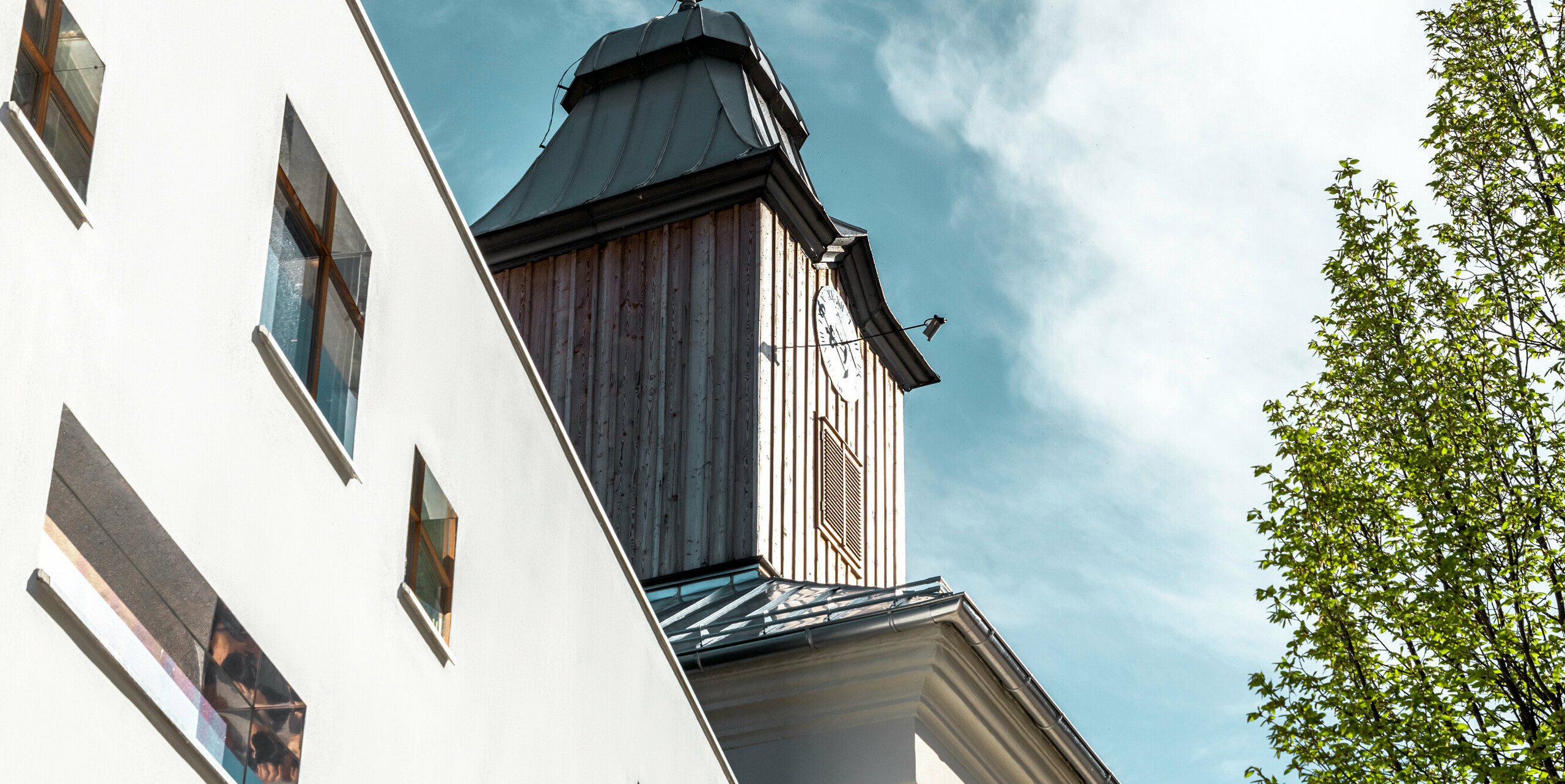 Das Dach des Hotels Glockenturm in Marktl bei Lilienfeld wurde mit der PREFA Dachschindel in P.10 Anthrazit verkleidet. Das PREFA Dachentwässerungssystem des Gebäudes ist in Naturblank gehalten. Unweit vom Hotel Glockenturm liegt das Leopold - unser Wirtshaus. Das Restaurantgebäude wurde ebenfalls mit PREFA Produkten eingedeckt.