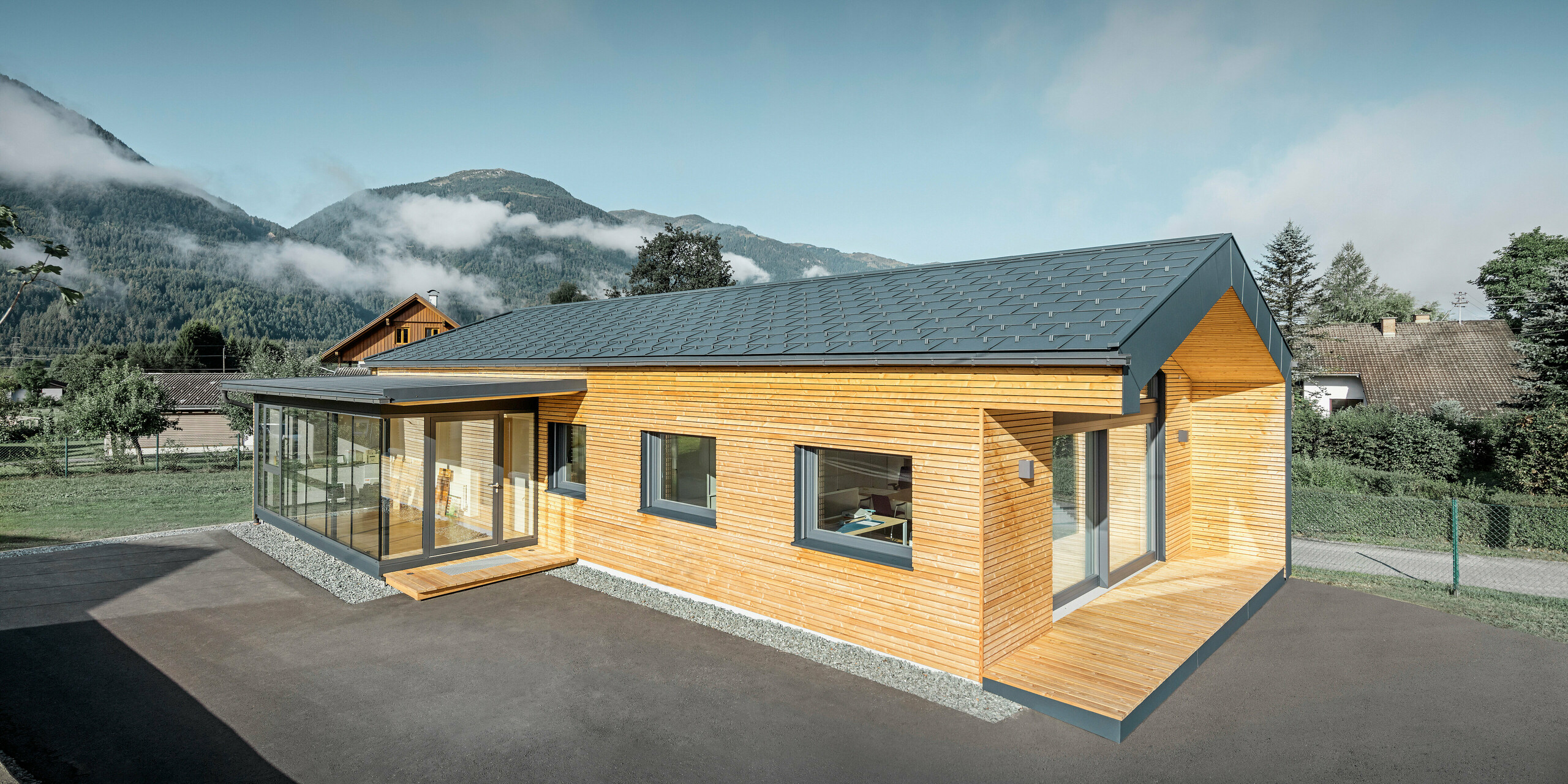 Modern office building with a larch wood façade and large windows. PREFA material in anthracite was used for the guttering.