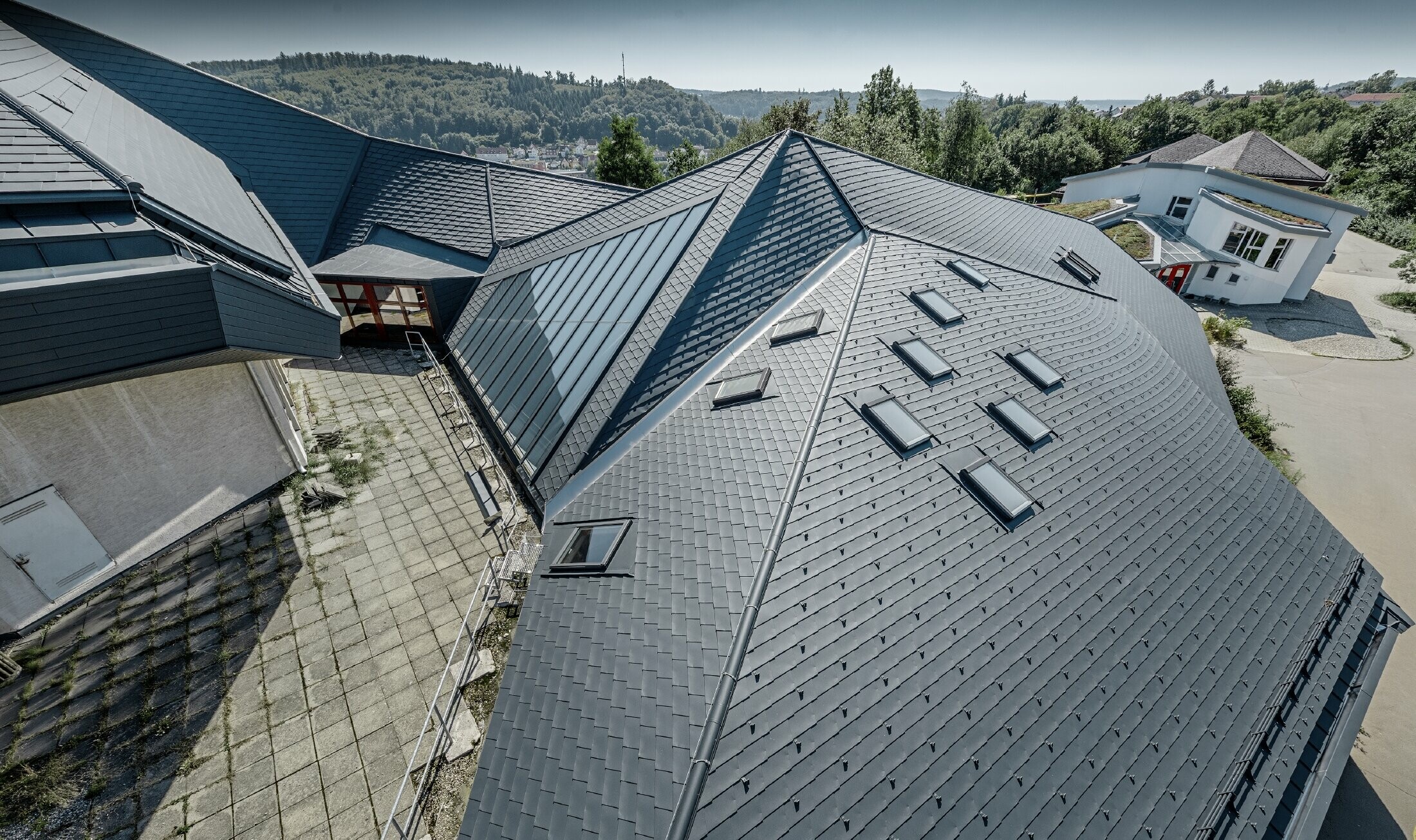 Waldorf school in Heidenheim (Germany) with a newly renovated roof. The large roof surface with its many angles and roof pitches was covered with PREFA shingle in anthracite