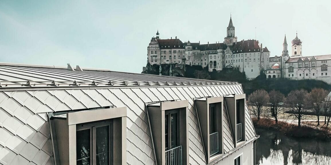 In the foreground, the PREFA roof in the colour bronze of the Karls Hotel Sigmaringen can be seen and in the background, the adjacent Sigmaringen Castle stretches out.