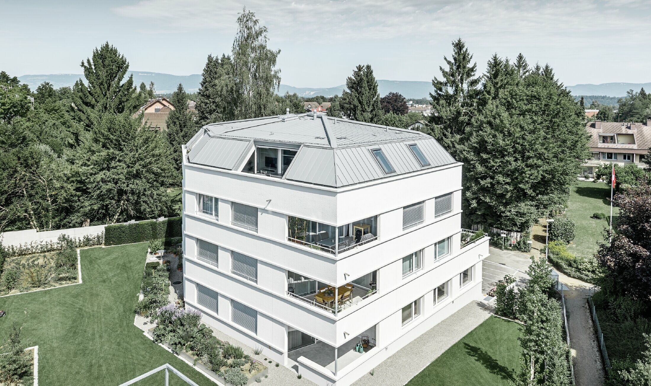 Modest apartment buildings with PREFA Prefalz in patina grey. The façade is rendered in white with large loggias on the outer corners.