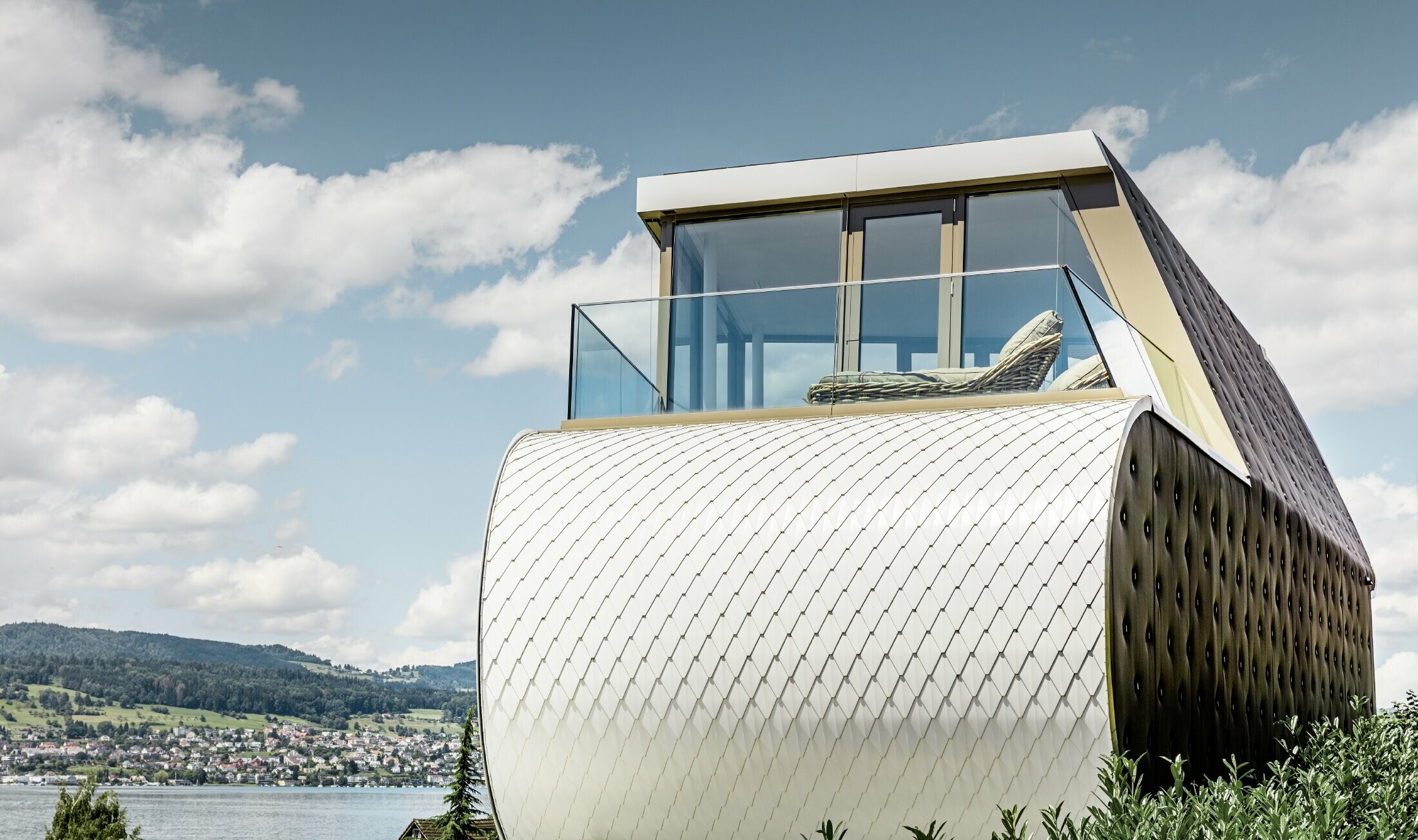 Side view of the excellent Flexhouse, designed by the architect Camenzind; you can see one of the curved exterior walls, which is clad with PREFA’s scale-like aluminium façade in pure white.