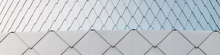 Close-up of the metallic silver façade made of PREFA rhomboid tiles that have been installed smoothly over the edges. The façade's flowing quality is clearly visible.