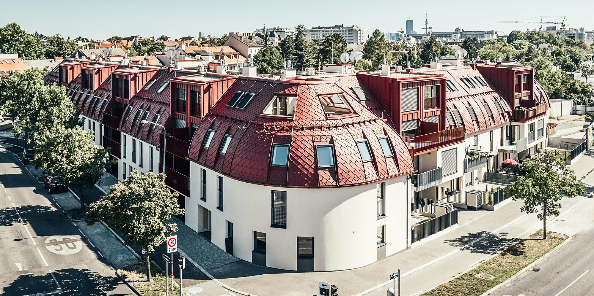 Street view of the residential complex Schöneck 13 with a rounded roofscape, designed by the architectural office schneider+schumacher.