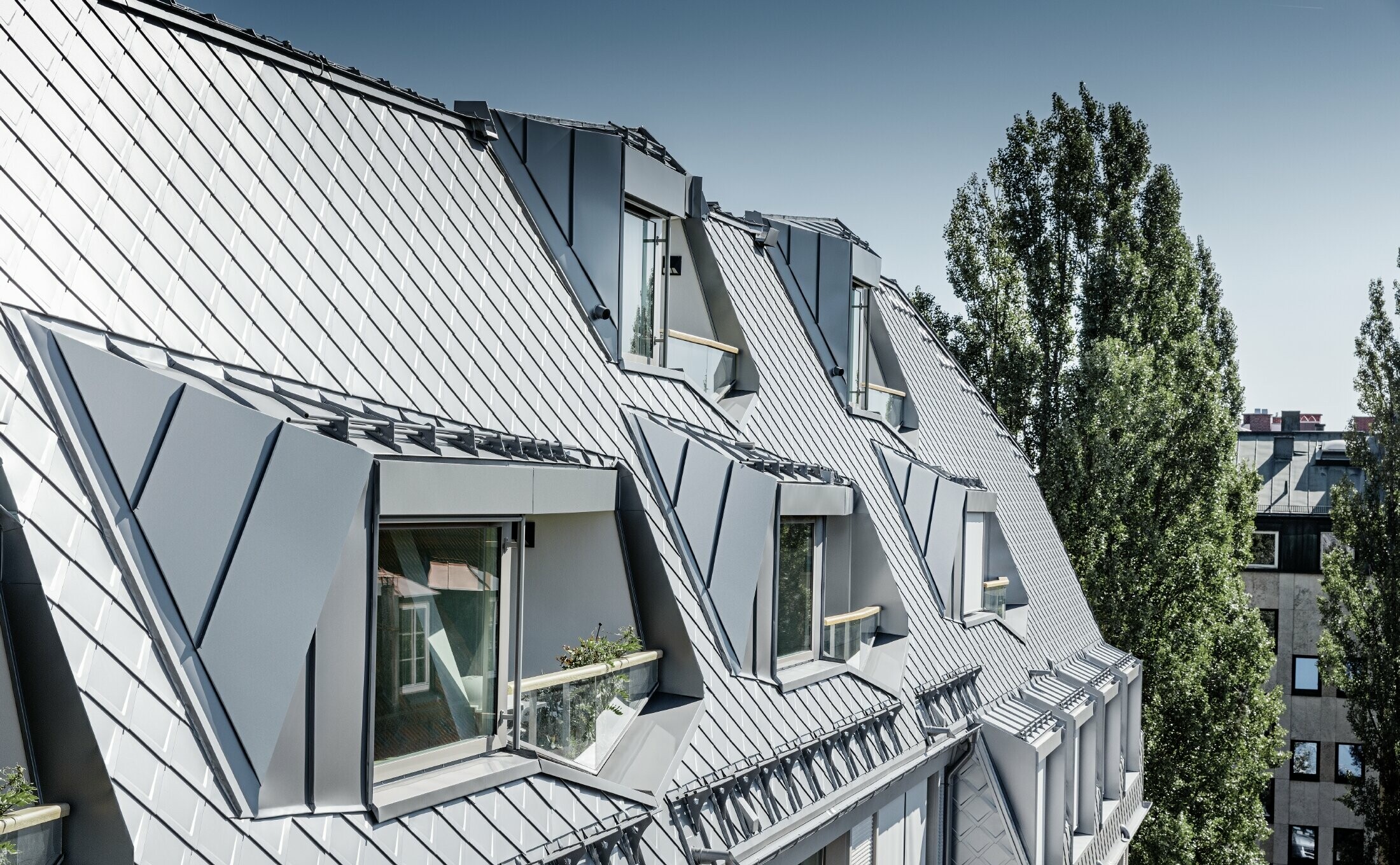 Renovated mansard apartments with large, open galleries in a residential and commercial building in Leopoldstraße/corner of Hohenzollernstraße in Munich (Germany), with a roof covering made of PREFA rhomboid roof tiles