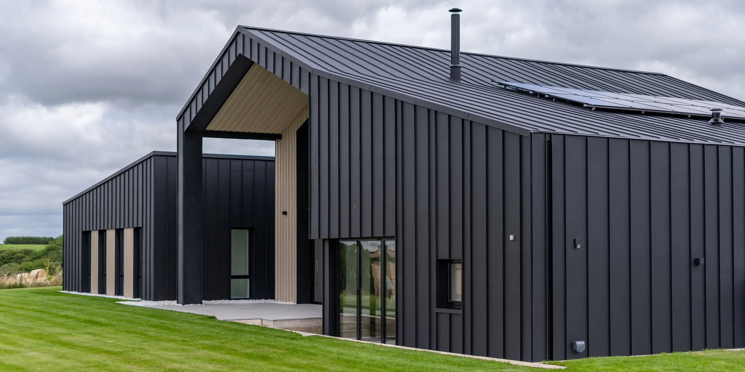 An oblique view of the back of ‘The Hide’ in Cornwall with PREFALZ roof and façade cladding in P.10 anthracite. The clear standing seam look of the aluminium roof and façade creates modern and harmonious lines, which are complemented by wooden elements and the surrounding nature – a perfect interplay of functionality and aesthetics.