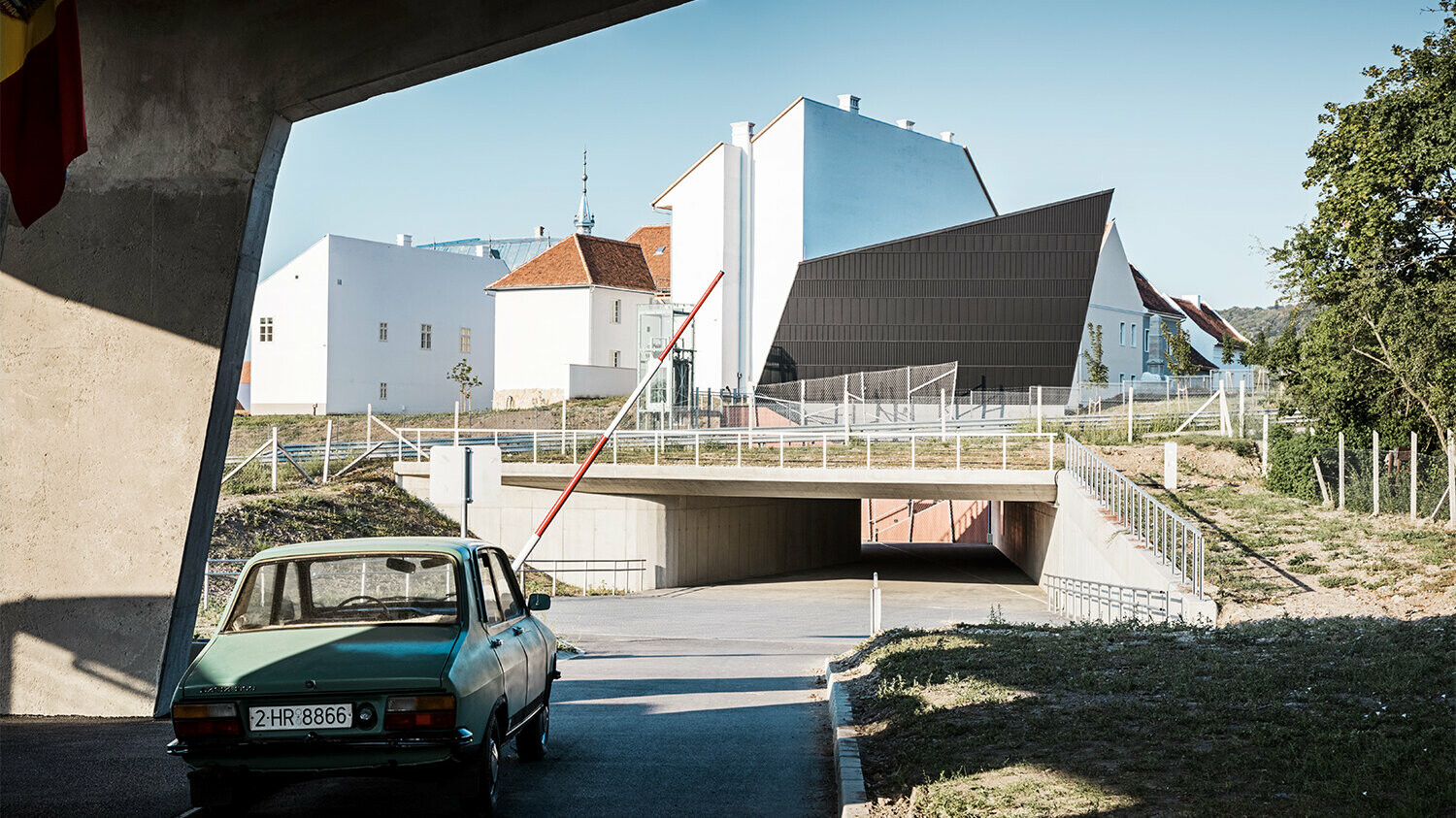 Side view of part of the open air museum inlcuding the cinema pavilion, a car in the lower left-hand corner of the photo is driving through the entrance in front of it.