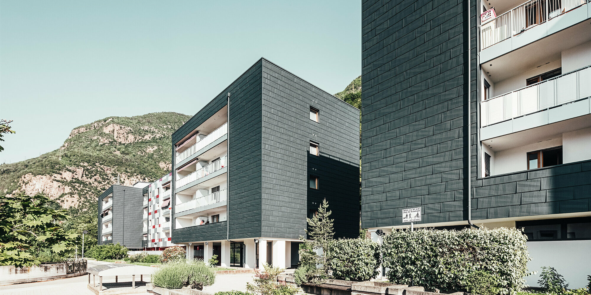 Diagonal view from the front of the renovated residential building in Bolzano. Balconies with white railings and house façade realised with the product facade panel FX.12.