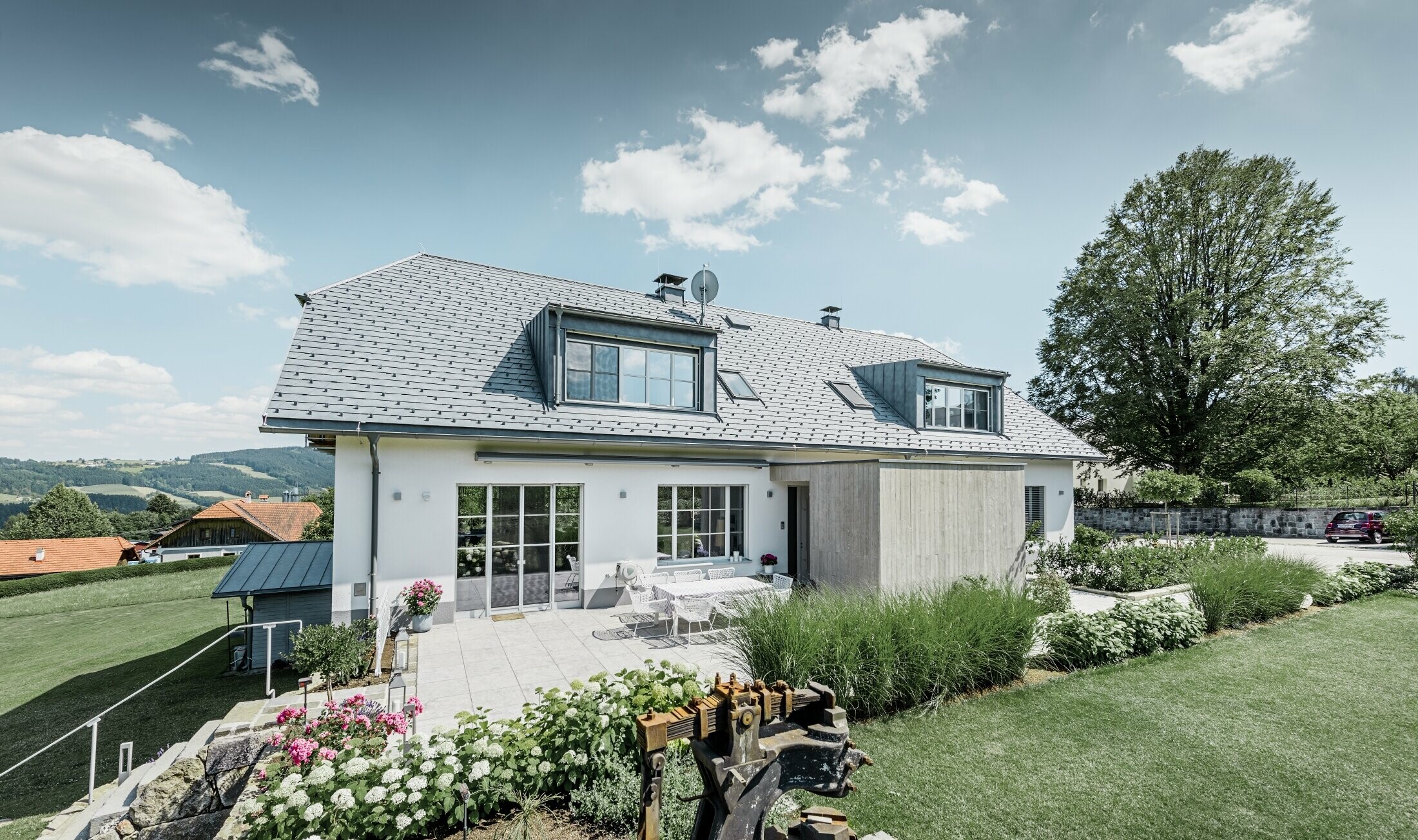 Classic detached house with a half-hipped roof; the house sporting a roof renovation with PREFA roof shingles in stone grey, with beautifully landscaped garden and spacious terrace.