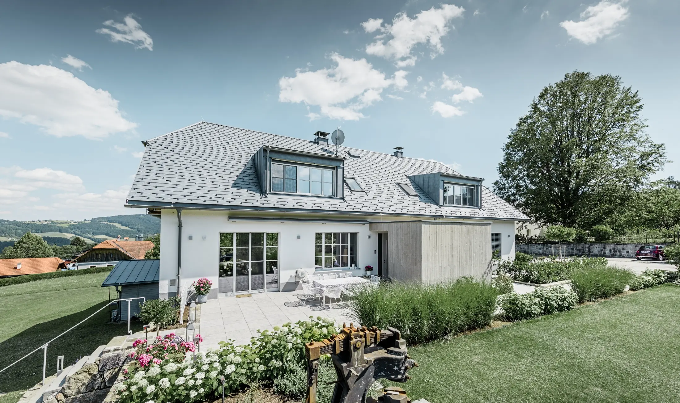 Classic detached house with a half-hipped roof; the house sporting a roof renovation with PREFA roof shingles in stone grey, with beautifully landscaped garden and spacious terrace.