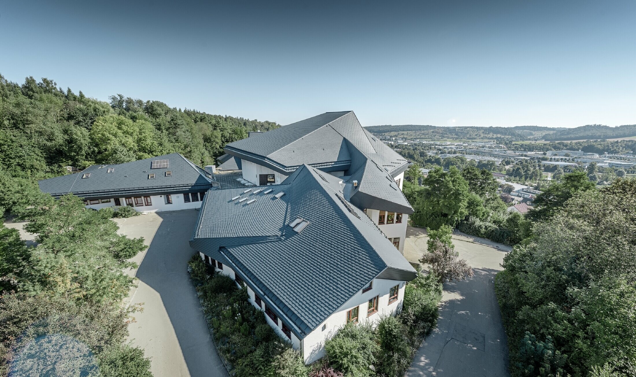 Waldorf school in Heidenheim (Germany) with a newly renovated roof. The large roof surface with its many angles and roof pitches was covered with PREFA shingle in anthracite