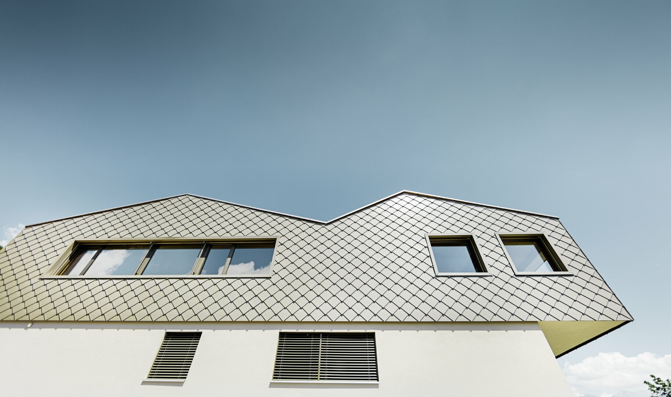 Modern detached house in the middle of the vineyards of the Rhône Valley with 4 different roof surfaces and an open gallery with a rhomboid tile façade in bronze