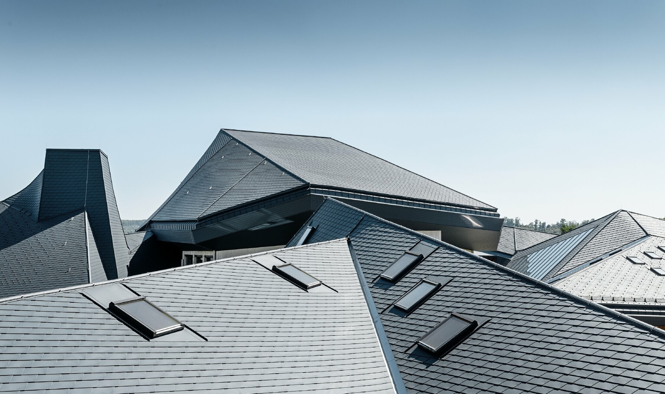 Waldorf school in Heidenheim (Germany) with a newly renovated roof. The large roof surface with its many angles and roof pitches was covered with PREFA shingle in anthracite