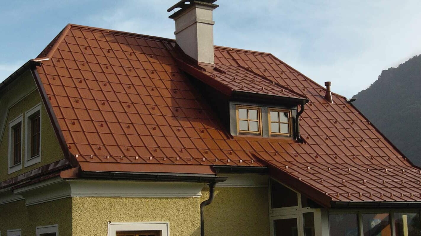 Detached house with a half-hipped roof and dormer with a newly renovated roof with PREFA roof tiles in brick red