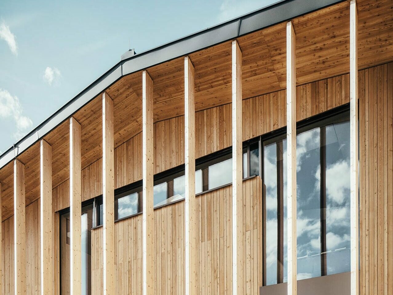 Close-up of the building. The wooden façade fits perfectly with the roof made of Prefalz in P.10 anthracite.