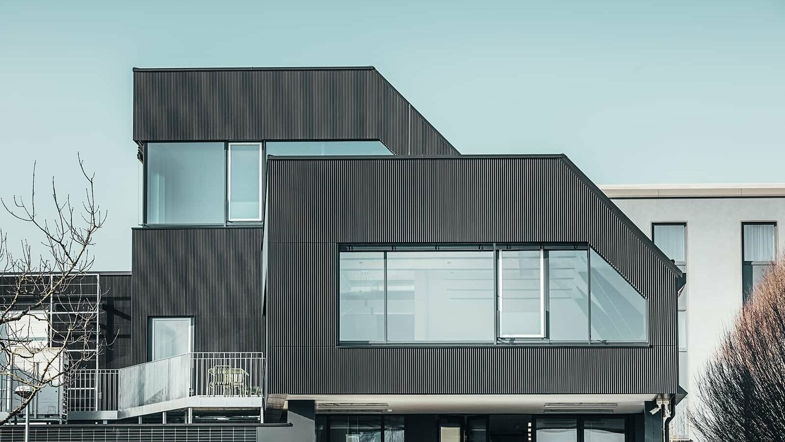 Side view of the Amann café on a sunny day. A corrugated profile in black was used to protect the building.