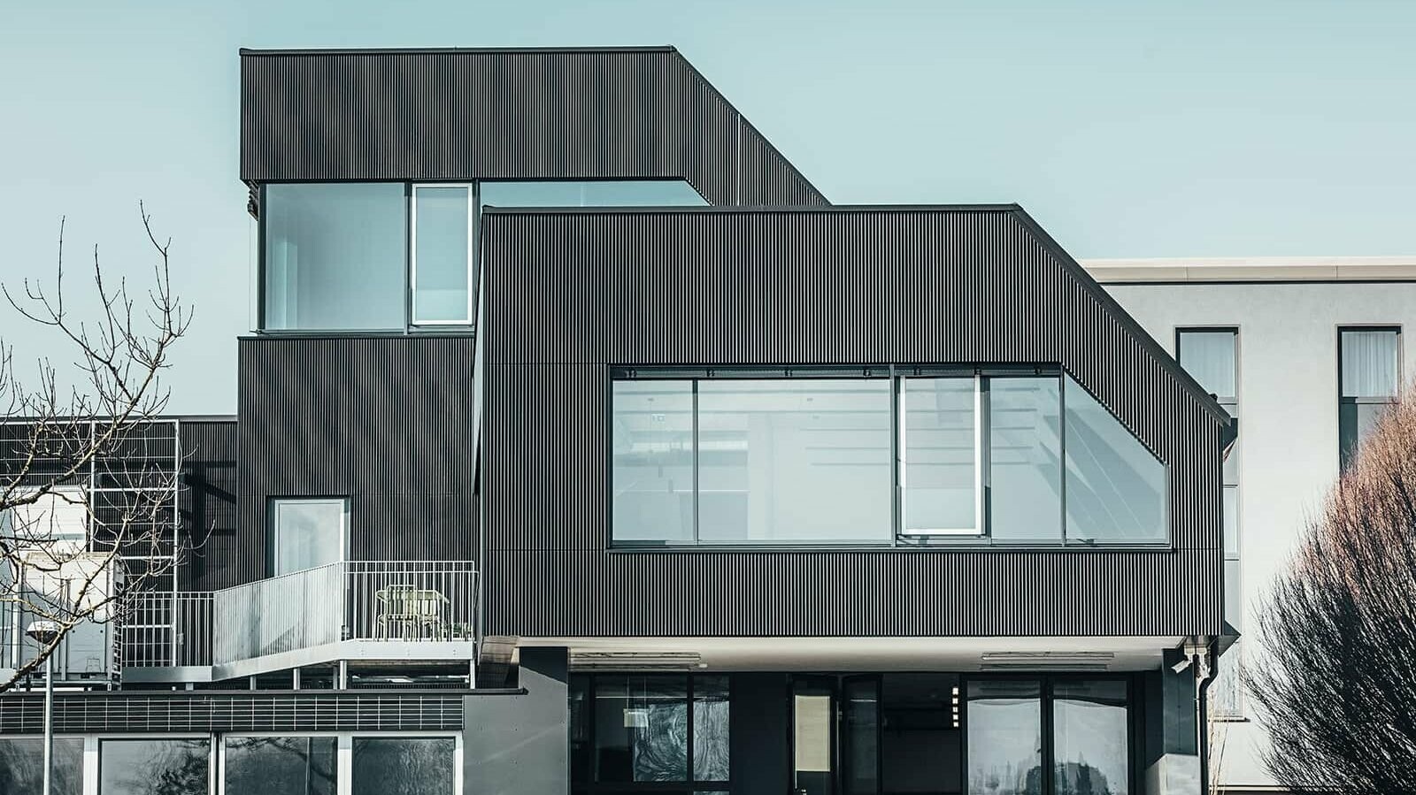 Side view of the Amann café on a sunny day. A corrugated profile in black was used to protect the building.