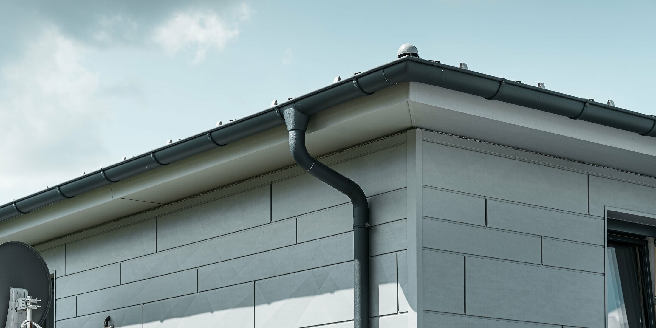 Roof soffit with PREFA gutter, gutter outlet and downpipe in anthracite with PREFA Siding.X façade in patina grey