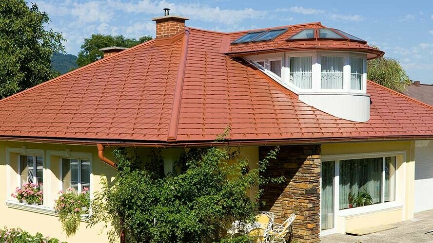 Detached house with hipped roof and dormers with PREFA brick red tile-effect aluminium shingles.