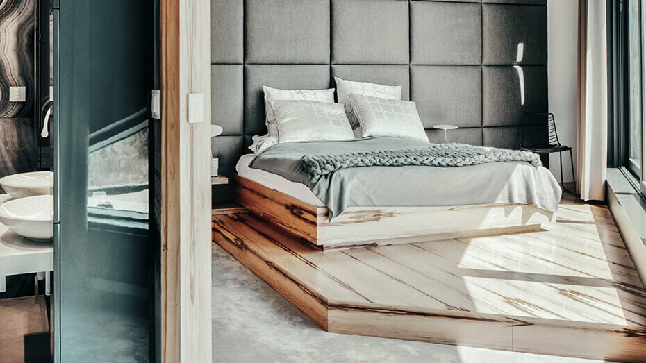 A view into the bedroom of the architect's house. A large comfortable bed adorns the pleasant ambience, on the left side is a short section of the modern bathroom.