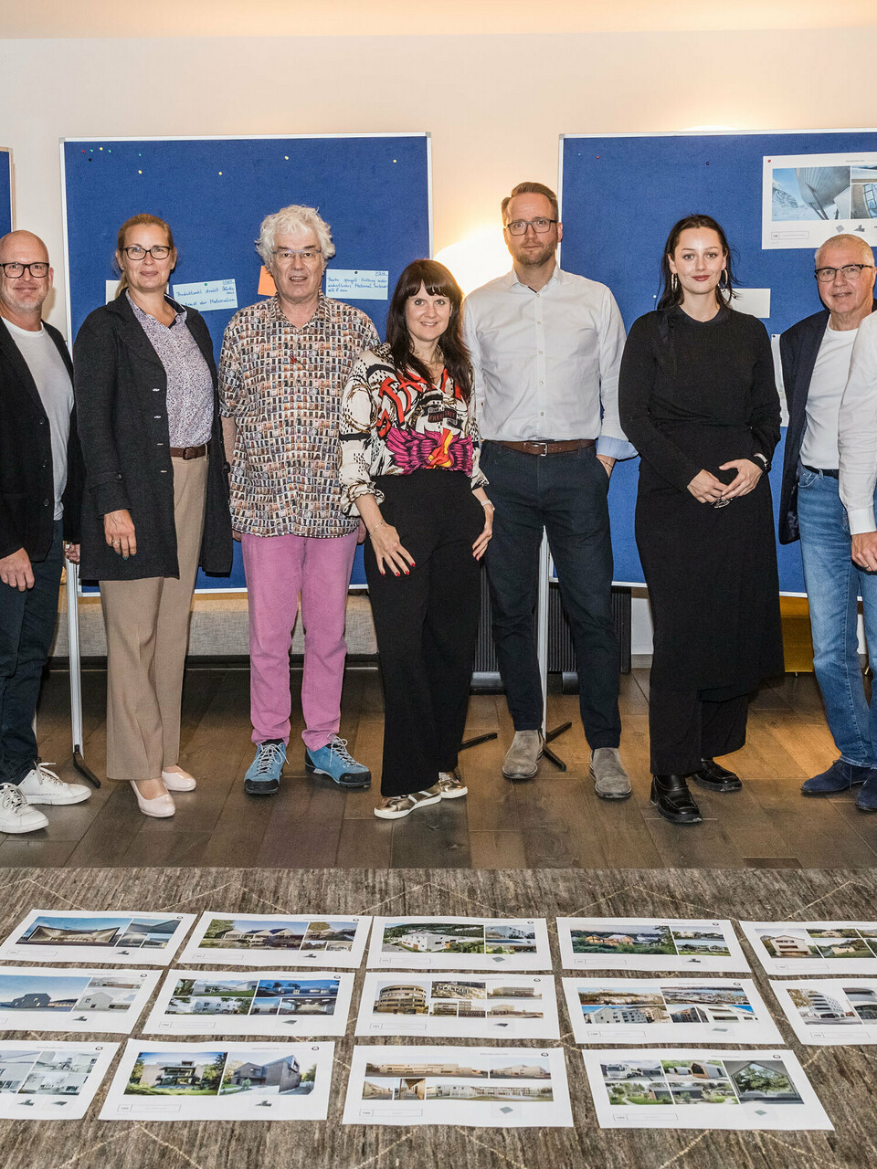 Group photo of the PREFARENZEN 2026 jury after the successful selection process in a winegrower's residence in Seewinkel, Burgenland: The interdisciplinary group of experts consisting of Dirk Lorenz (Leinert Lorenz Architekten), Veronika Roll (Marketing, PREFA Austria), Wolfgang Croce (Croce & Wir, Graz), Jürgen Jungmair (Head of International Marketing, PREFA), Judit Nemere (Managing Director, PREFA Hungary), Matthias Finkentey (Moderator), Bettina Almeida (Communications Management, PREFA), Christian Wirth (Regional Manager East, PREFA Austria), Selina Wach (Head of Discourse, Architektur Aktuell), Thomas Schlett (B3 Architekten), Sven Disser (Head of Development, Bauwerk), Falk Leinert (Leinert Lorenz Architekten) and Juliane Croce (Croce & Wir, Graz) stands in front of the final architectural projects selected for the PREFARENZEN architecture book and the 2026 calendar. The projects reflect diversity, sustainability and innovative use of PREFA materials.