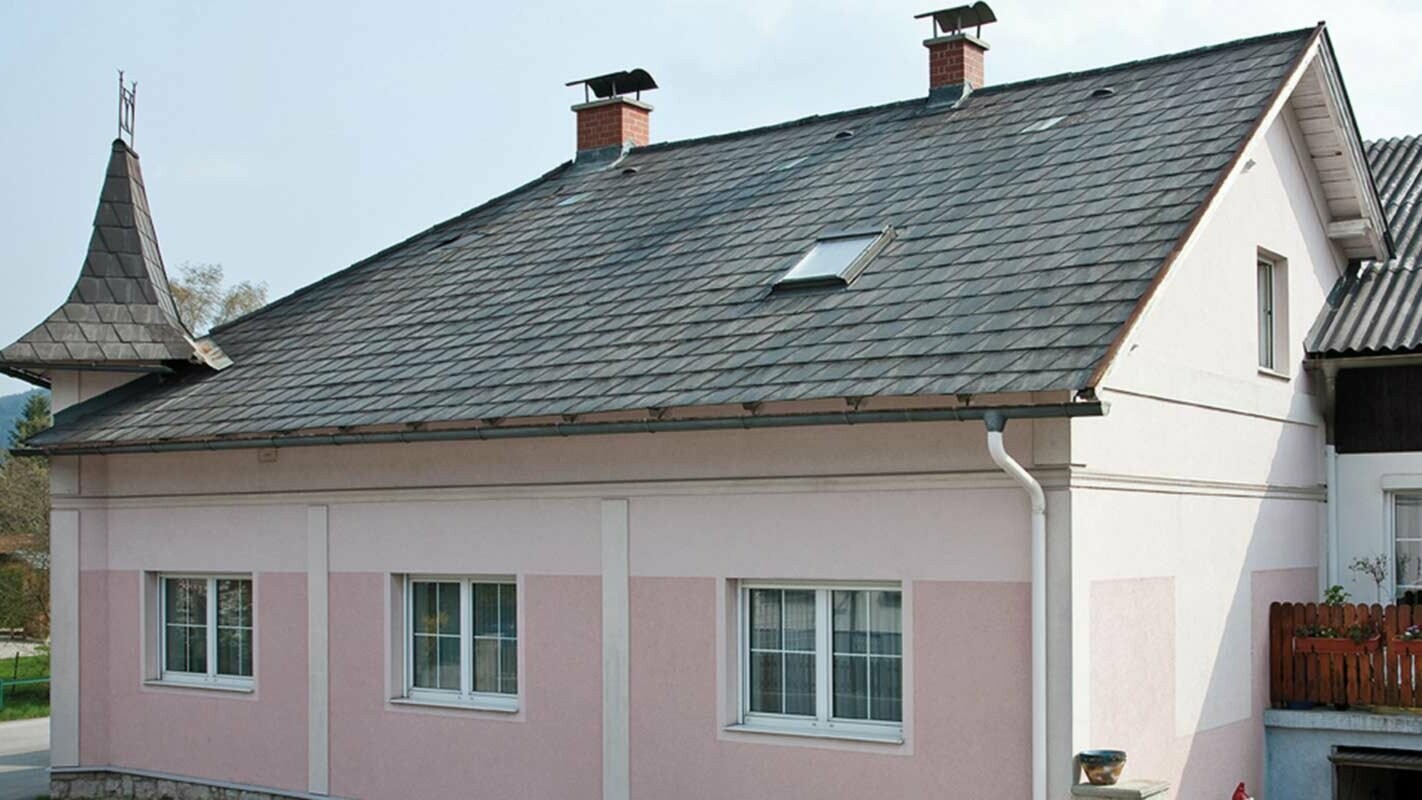 House before roof renovation with PREFA roof tiles in Austria - before: Eternit fibre cement with a turret and a pink façade