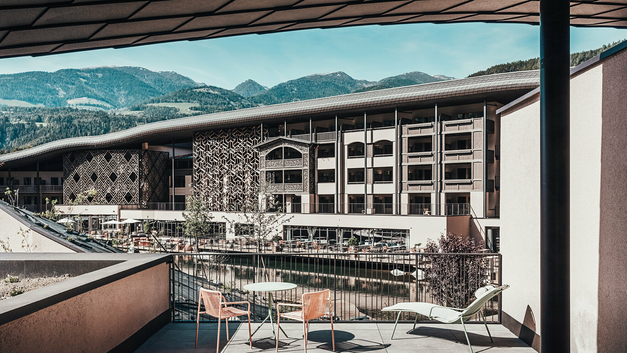 A view of the Falkensteiner Hotel from the terrace. Hilly mountain landscape can be seen in the background.