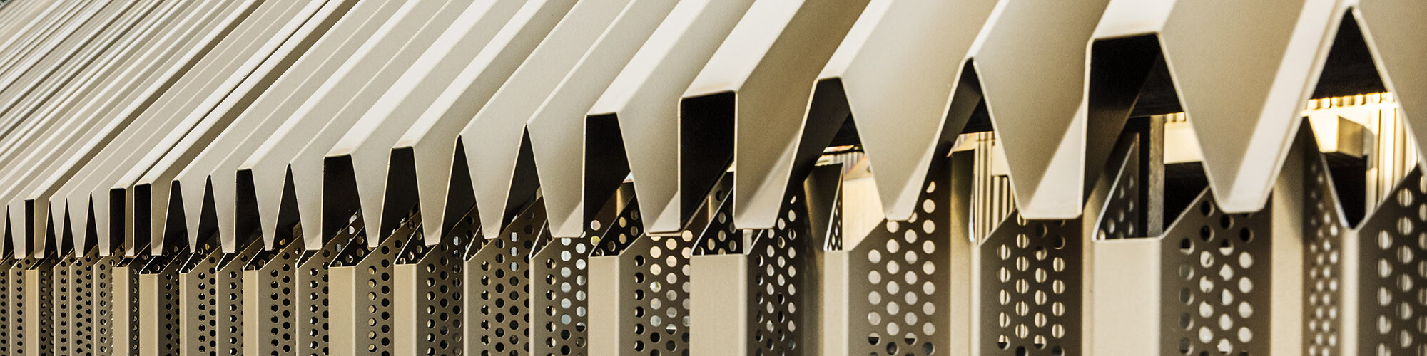 Close-up of the transition between the roof and façade: The specially edged and perforated PREFA aluminium sheets in the colour bronze makes the building envelope unique.