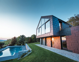 Aluminium façade of a detached house with PREFA FX.12 façade panels in P.10 anthracite at sunset. 