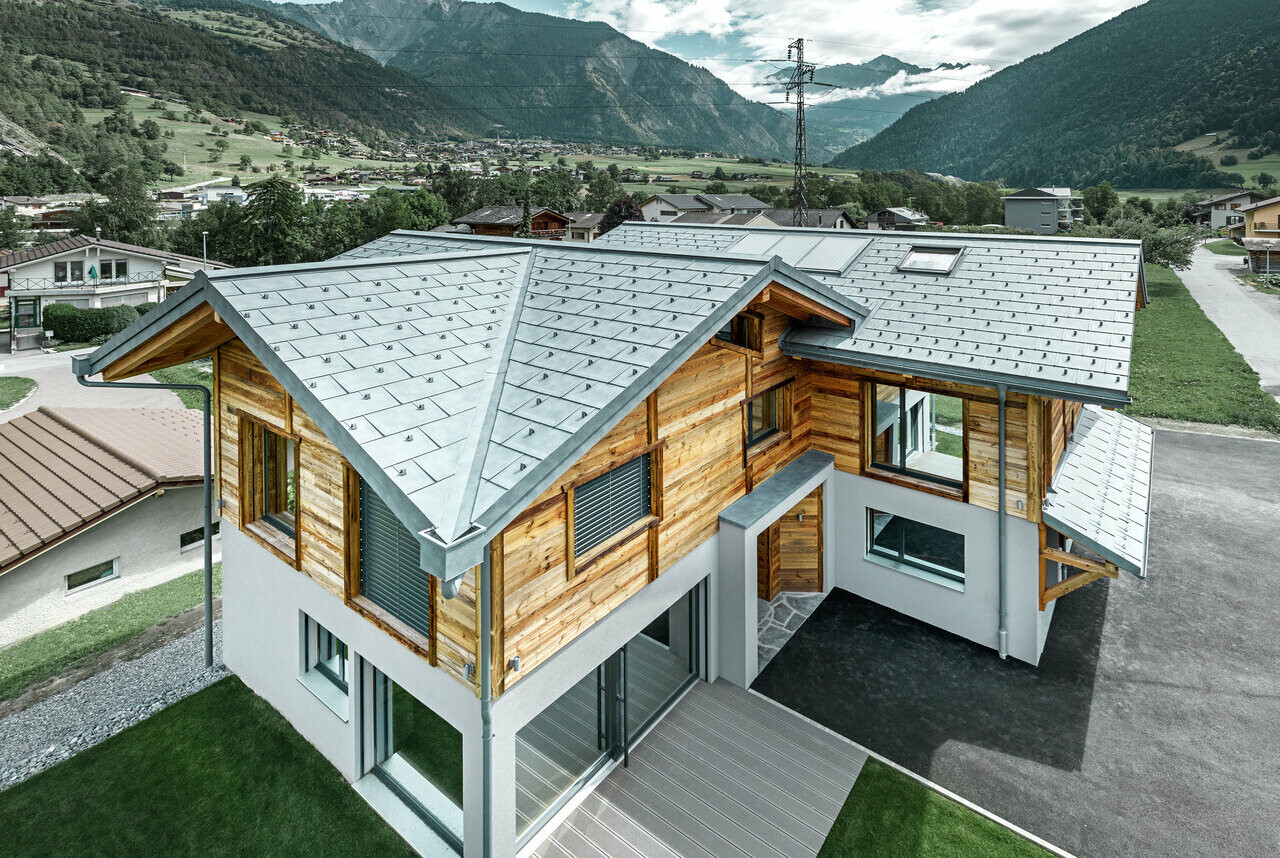 Swiss chalet with aluminium roof by PREFA. The R.16 roof tile in stone grey was installed. A rustic wooden façade was used for the top floor.