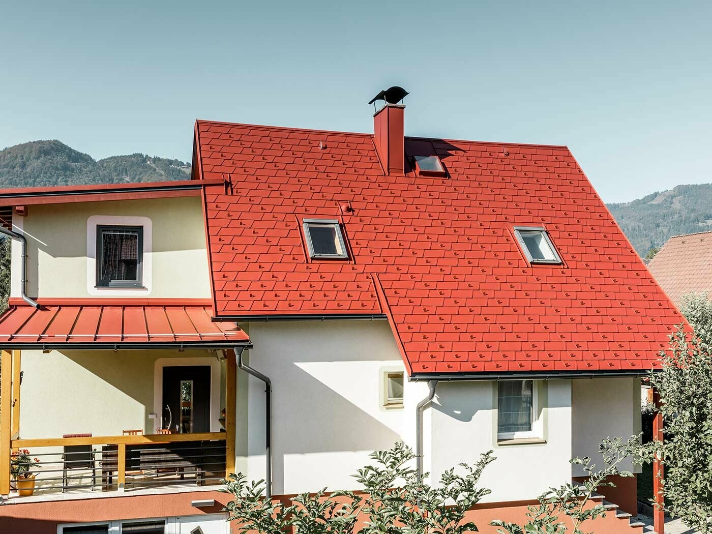 Classic single-family house with two skylights and chimney, roofed with the new PREFA DS.19 shingle in P.10 oxide red.