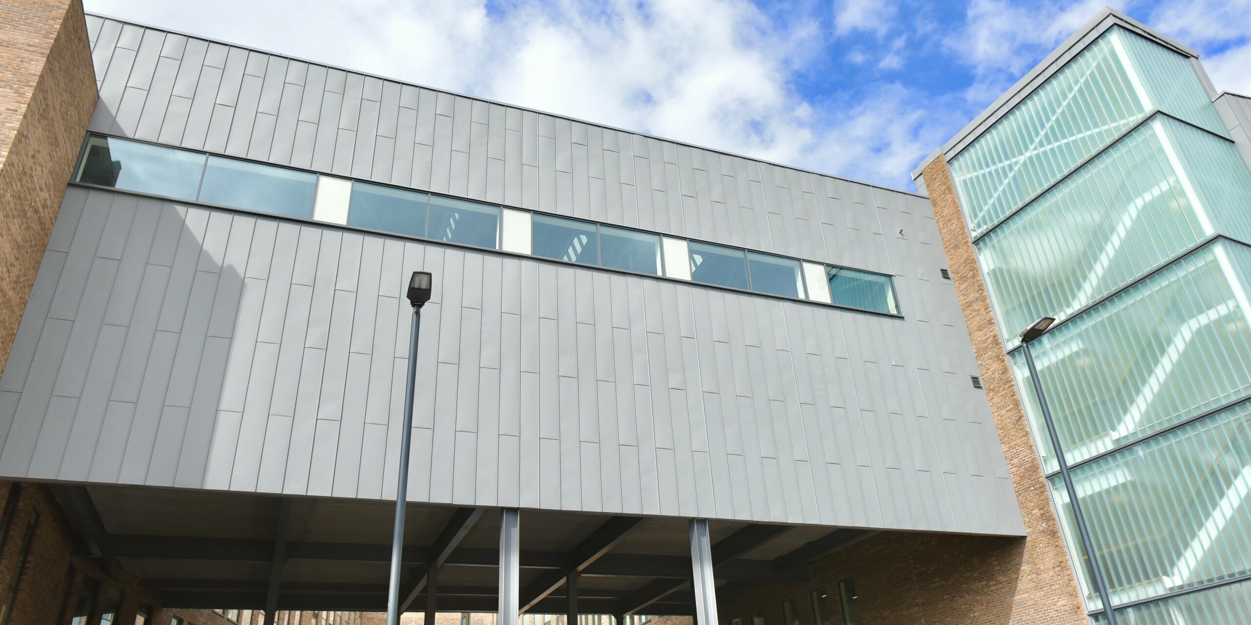 North Regional College in Coleraine, with its PREFALZ aluminium façade in patina grey. The innovative standing seam roof gives the educational institution a sense of lightness and robustness at the same time. The façade made of aluminium and brick harmonises and gives the building a timeless architectural look.