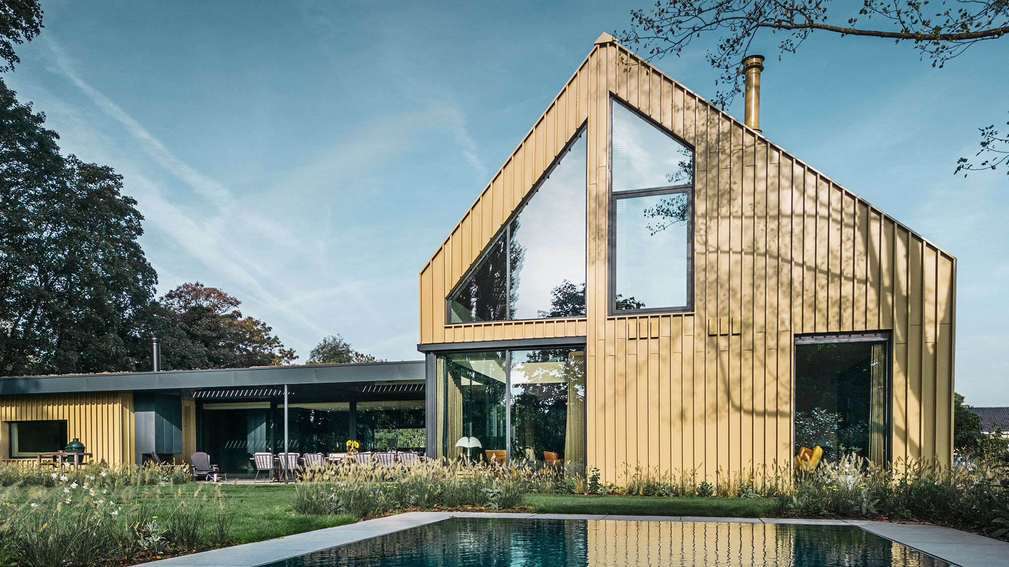 A view of the back side of the house with the generous glass front and the pool.