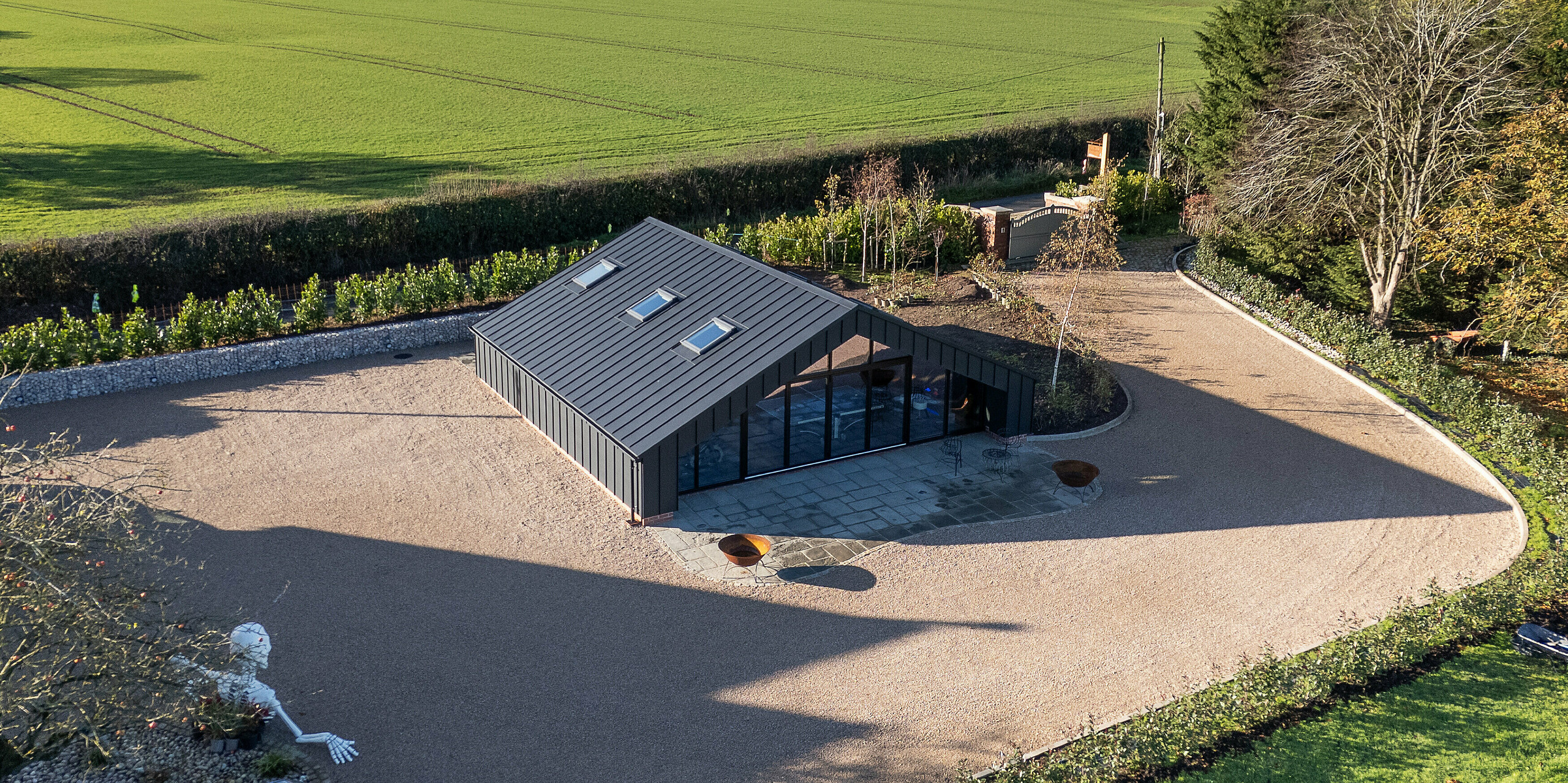 Wide aerial view of the modern leisure building clad entirely with PREFA aluminum and PREFALZ standing seam roofing in P.10 black. The precise seam lines, striking roof geometry and expansive glass façade create a bold architectural presence. The durable, weather‑resistant aluminum envelope blends seamlessly into the surrounding open landscape.