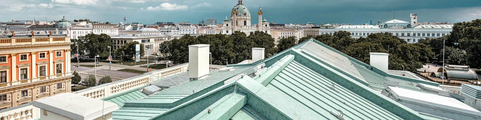 View of the roof covered in Prefalz P.10 patina green. Several buildings are in the background.