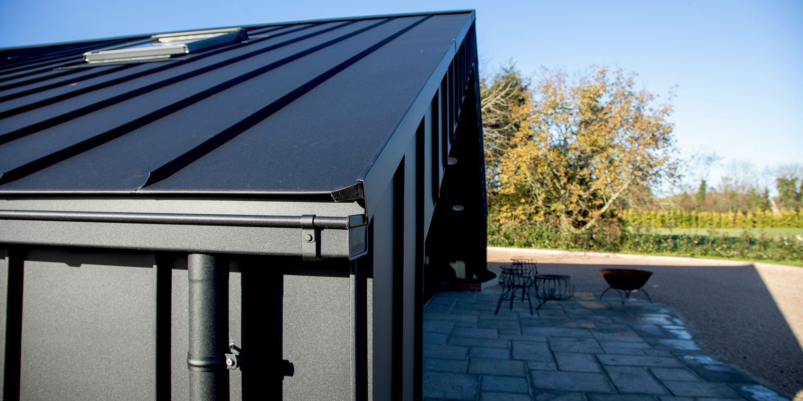 Close-up of the modern PREFA building envelope featuring PREFALZ in P.10 black. The clean standing seam lines and precisely engineered aluminum eaves highlight the building’s sleek, contemporary design. The durable, weather‑resistant aluminum surface ensures long‑lasting protection while seamlessly integrating the structure with its surrounding outdoor area.