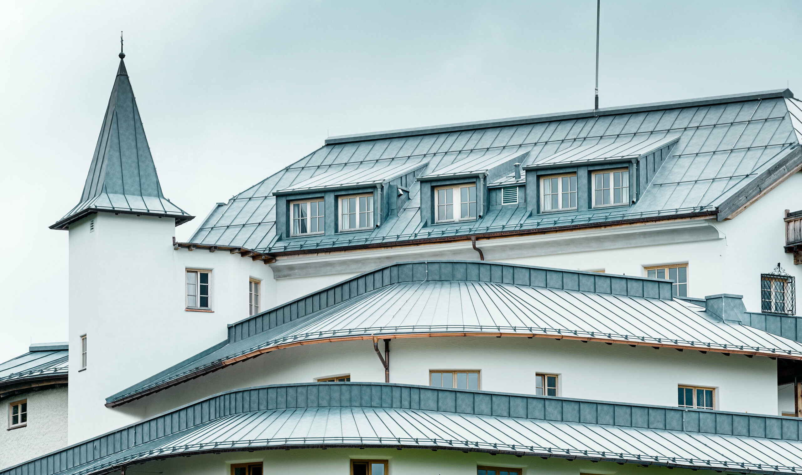 Mittersill Castle surrounded by trees and mountains with a recently renovated Prefalz roof in stone grey