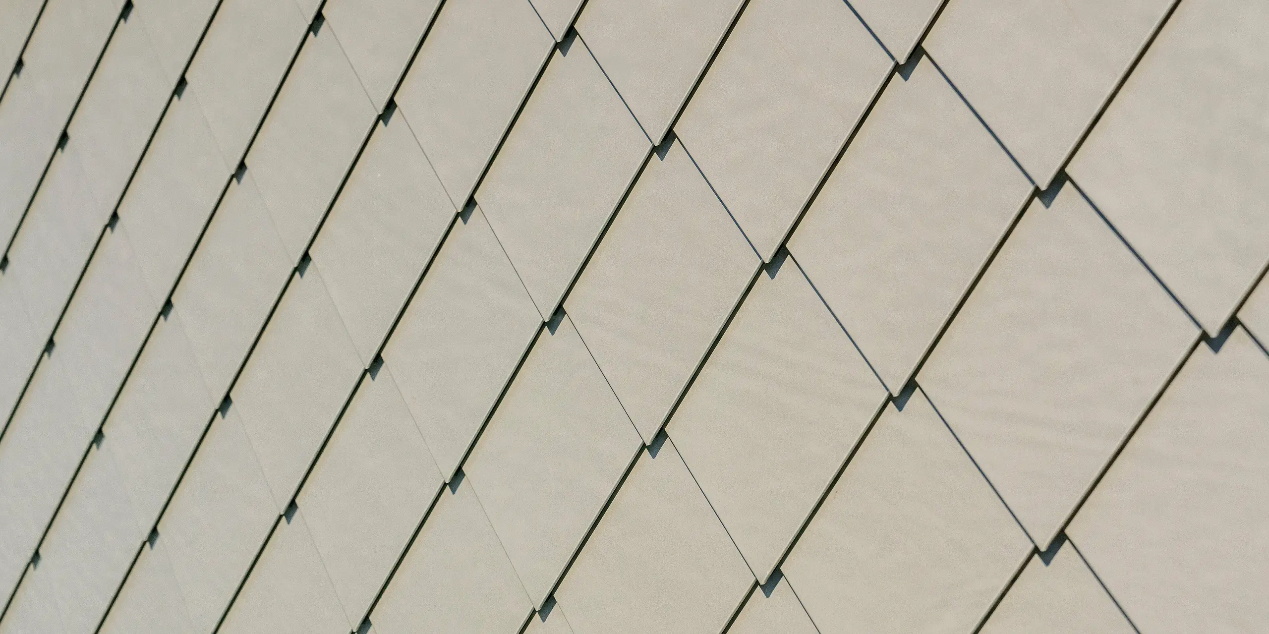 Detailaufnahme der PREFA Aluminiumfassade am Sporthotel Obereggen mit Wandraute 29 × 29 in der Farbe Bronze. Die präzise verlegten Rauten bilden ein ruhiges, geometrisches Muster mit feiner Oberflächenstruktur, die je nach Lichteinfall unterschiedlich wirkt. Der warme Bronzeton unterstreicht die hochwertige Ausstrahlung der modernen Architektur. Die langlebigen, witterungsbeständigen und wartungsarmen PREFA Aluminiumprodukte bieten nicht nur gestalterische Freiheit, sondern auch höchste Qualität und Sicherheit.