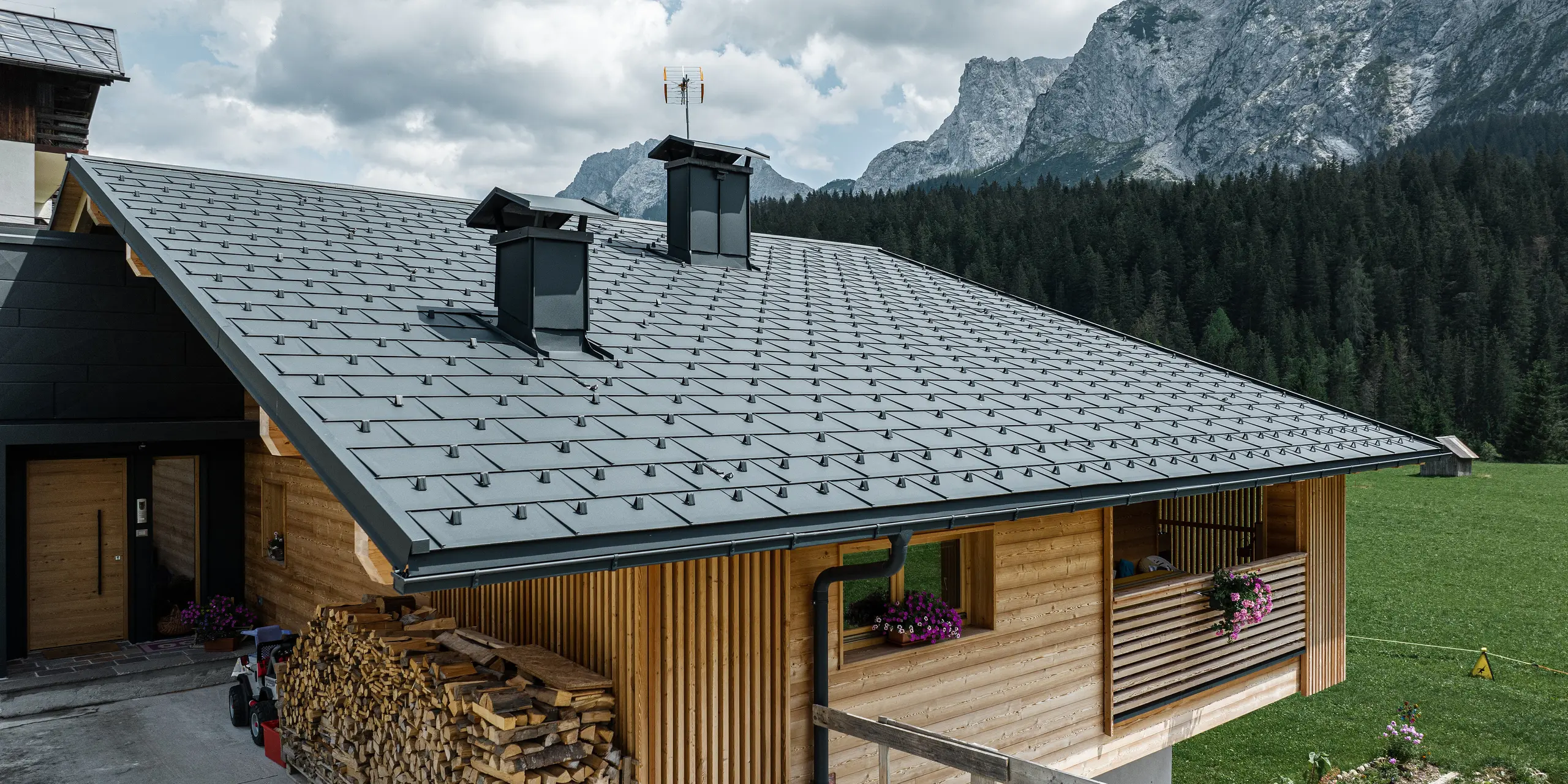 Casa Hoffe in Sappada, Italien, präsentiert ein schwarzes PREFA Dach, Die Dachplatten R.16, fügen sich harmonisch in die ländliche alpine Landschaft ein. Die dunklen, präzise angeordneten Aluminiumplatten kontrastieren stilvoll mit der hellen Holzfassade und sorgen für einen modernen Touch, der die traditionellen Werte des alpinen Wohnens widerspiegelt. Die robusten und langlebigen Materialien versprechen Schutz und eine geringe Wartung in der herausfordernden Bergumgebung.