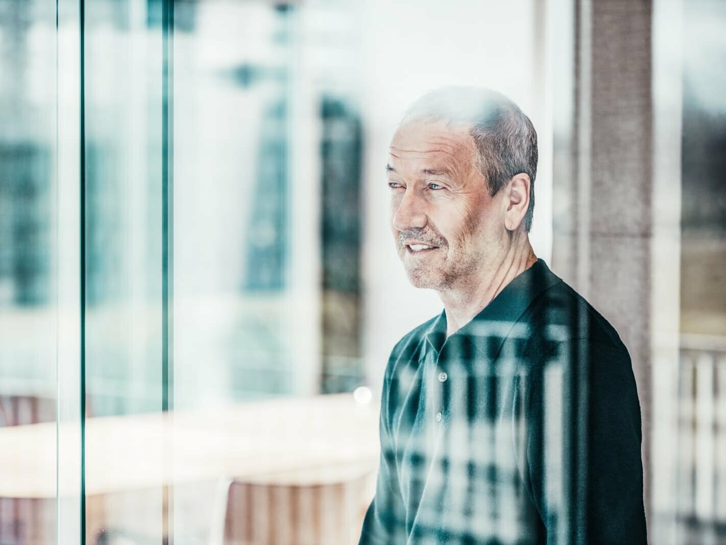 A portrait of the architect Arno Bereiter, who is looking through a window.