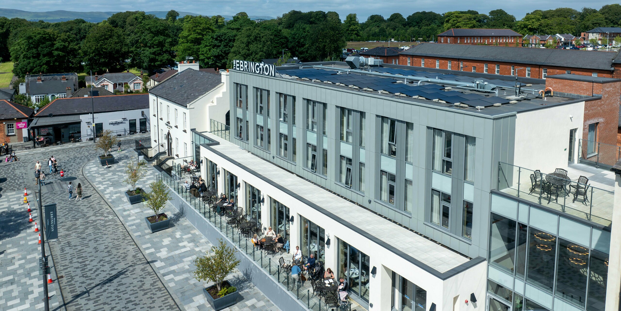 The Ebrington Hotel in the centre of Londonderry, Northern Ireland, has a modern aluminium façade. The upper floor is clad with PREFALZ in P.10 Light Grey and P.10 Zinc Grey, giving the building an elegant and robust appearance. In the foreground is the hotel's lively terrace, where guests can relax and enjoy the surroundings. The high quality sheet metal cladding contributes to the aesthetic and durable appearance of the hotel.