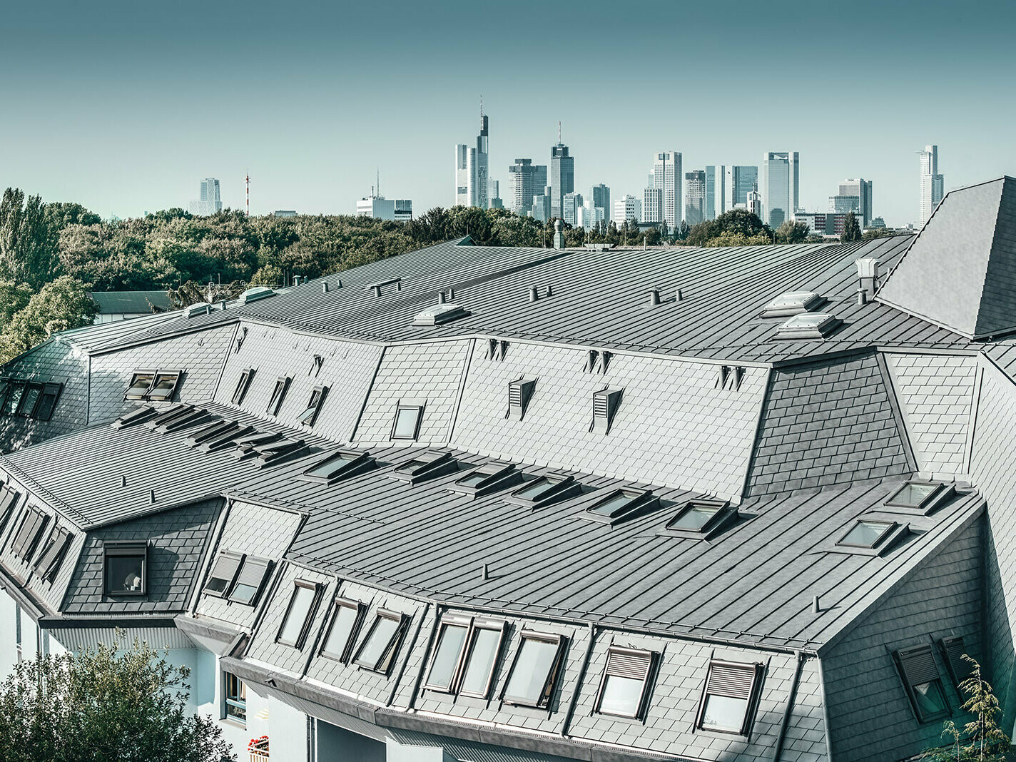 renovated roof landscape, side view of house with the Frankfurt skyline in the background, aluminium roof made of Prefalz and PREFA shingles, around 200 roof windows