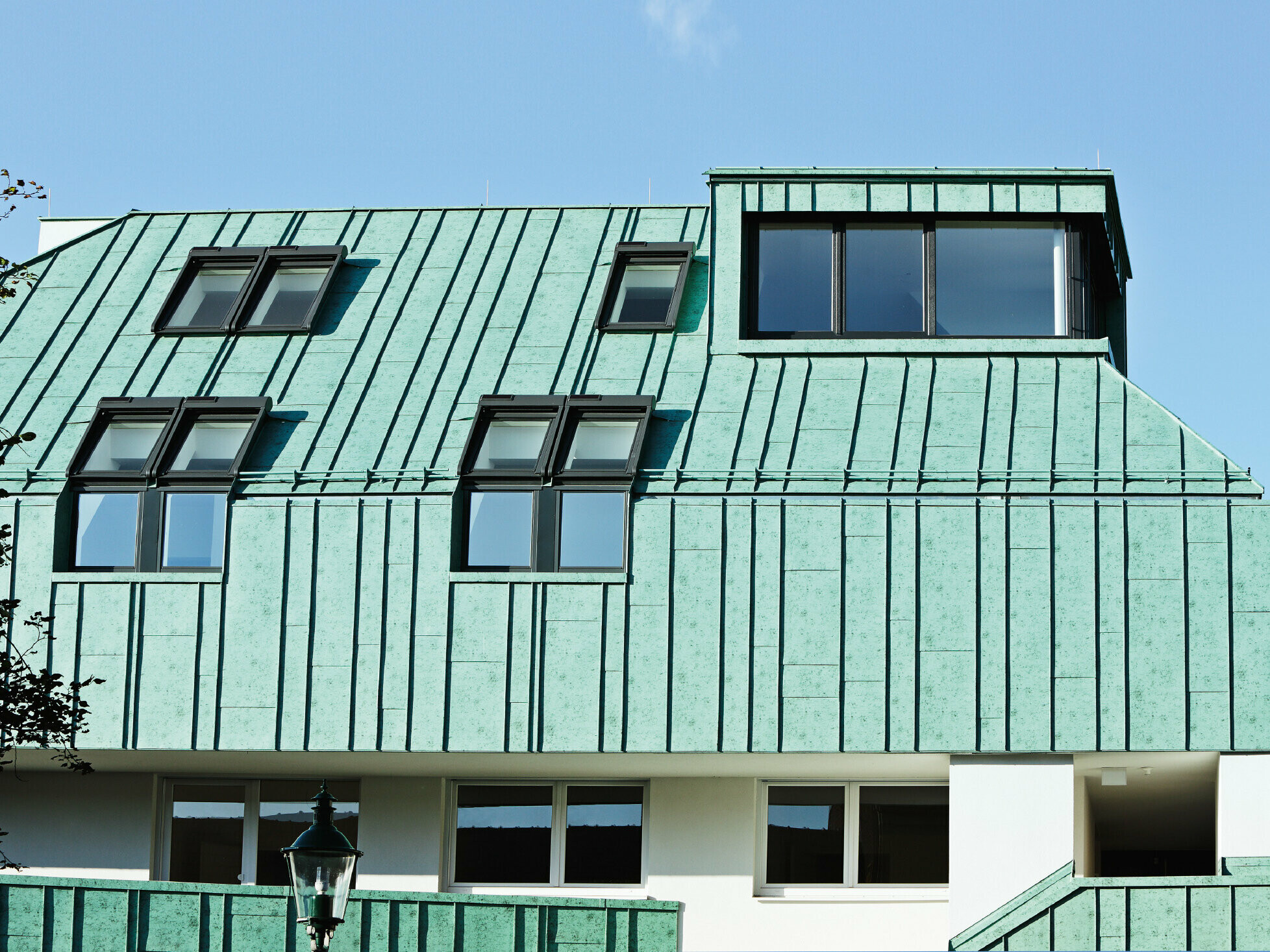 Roof and façade design with PREFALZ in patina green from PREFA in different panel widths.