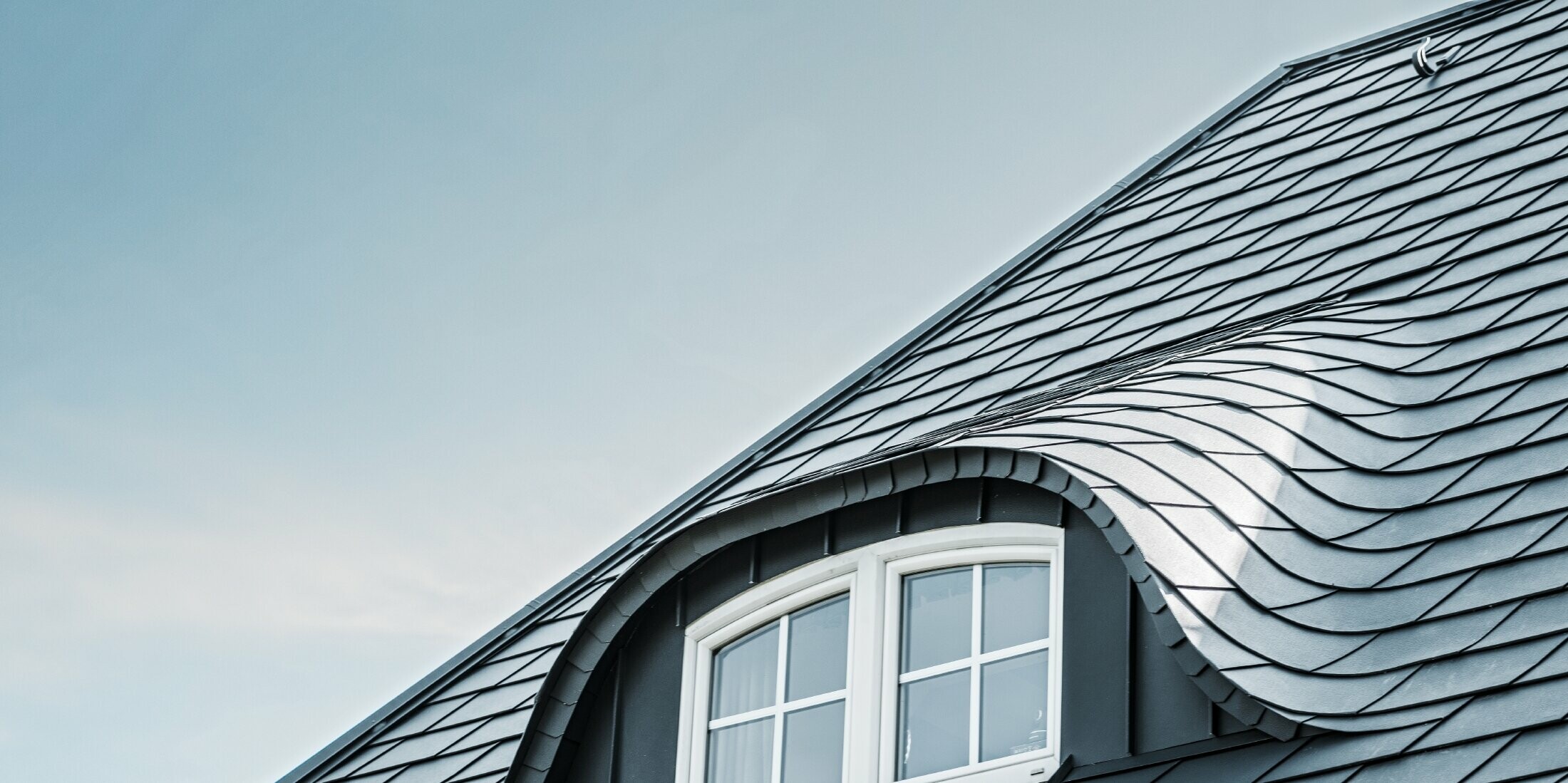 newly renovated roof with curved dormer with window covered with aluminium roof shingles by PREFA in P.10 anthracite 