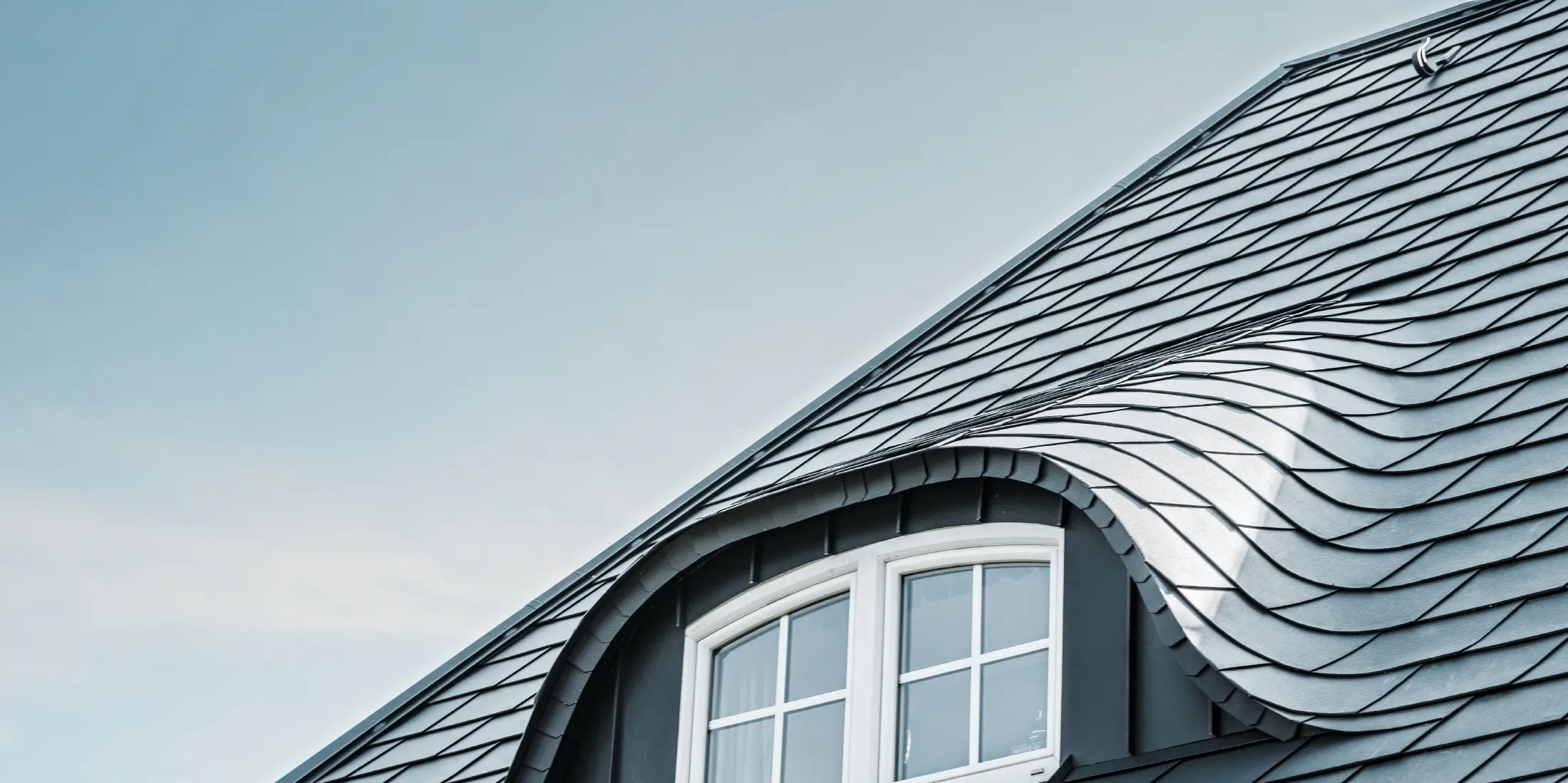 newly renovated roof with curved dormer with window covered with aluminium roof shingles by PREFA in P.10 anthracite 